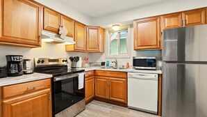 A kitchen with wooden cabinets, a stainless steel refrigerator, a microwave, an oven, and a dishwasher.