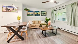 A modern living room with a dining table, sofa, and ceiling fans.