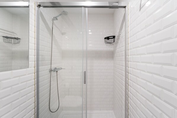 A glass-enclosed shower with white tiled walls and a chrome showerhead.