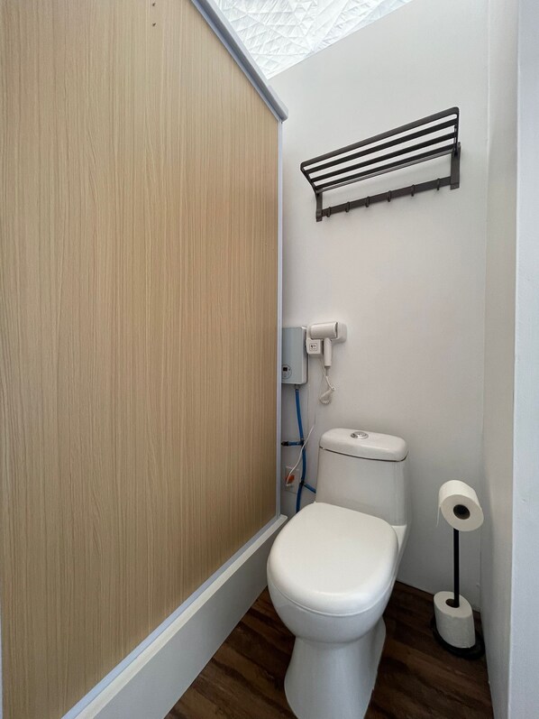 A small, modern bathroom with a toilet, a towel rack, and a toilet paper holder.
