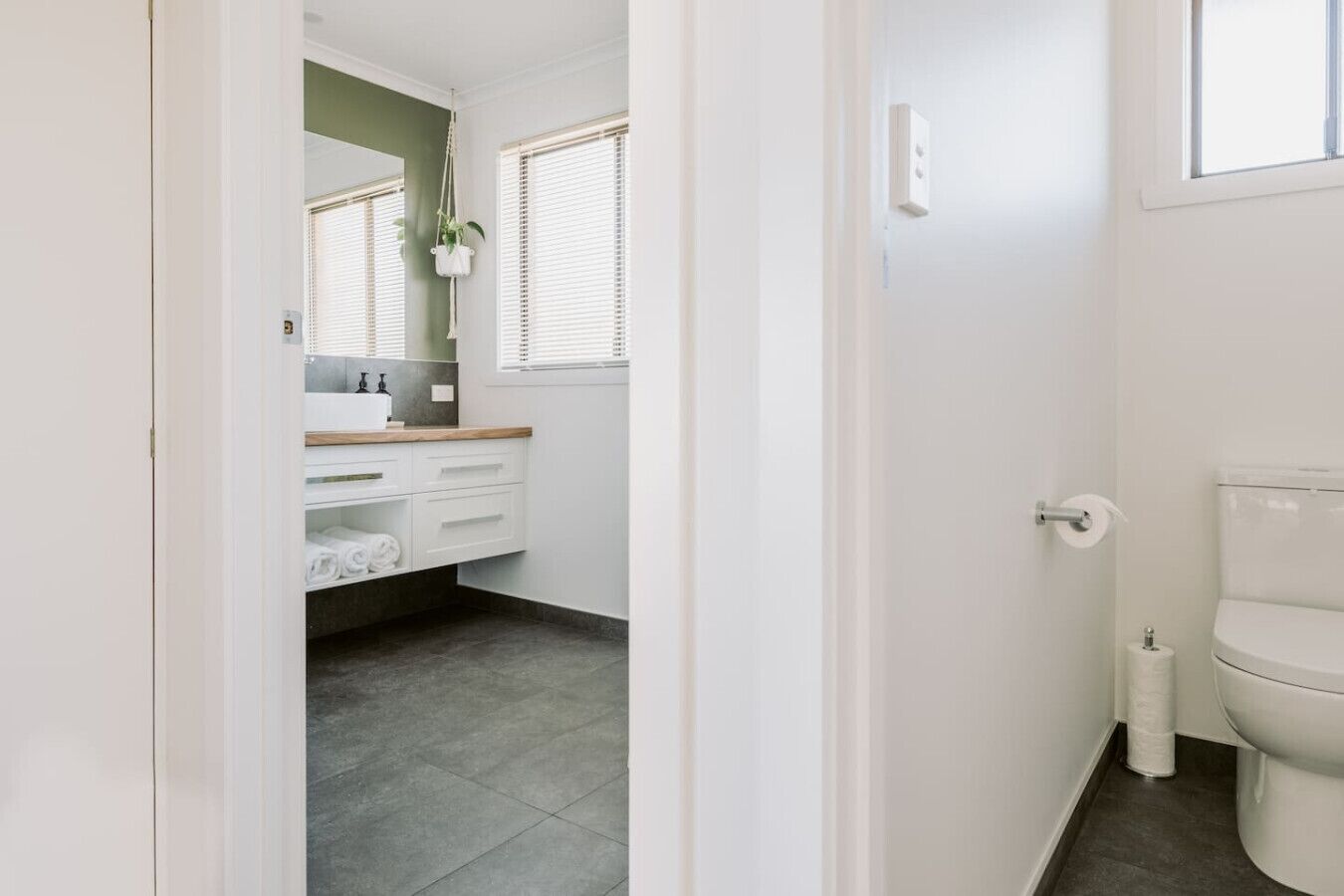 A bathroom with a toilet, a sink with a mirror, and a towel rack.