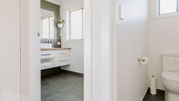 A bathroom with a toilet, a sink with a mirror, and a towel rack.