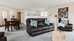 Ein modernes Wohnzimmer mit einer Ledersofa, einem Esstisch und einer Küche im Hintergrund.