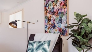 Ein modernes Schlafzimmer mit einem dunkelbraunen Ledersofa, einem großen Blumenbild, einer Stehlampe und einem Blumentopf.