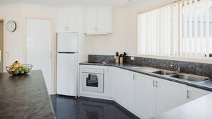 Eine moderne Küche mit weißen Schränken, einem eingebauten Backofen und einer Arbeitsplatte aus Granit.