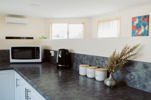 A kitchen with a microwave, coffee maker, and jars on the counter. - The Sanctuary Devonport (Devonport)