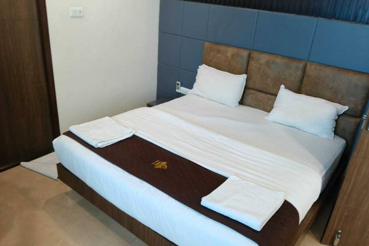 A neatly made bed with white linens and a brown headboard.
