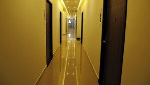 Un couloir d’hôtel avec des portes de chaque côté, un sol brillant et un éclairage encastré.