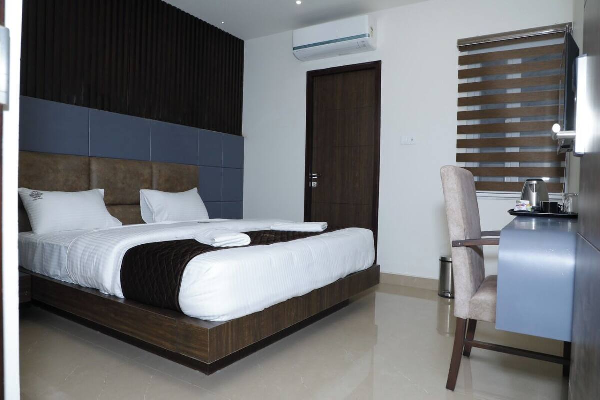 A modern hotel room with a large bed, a desk, and a chair.