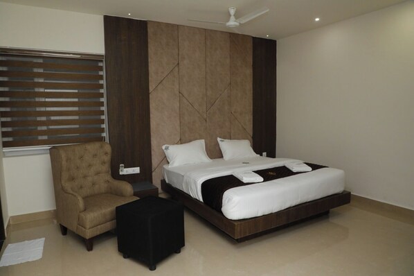 A modern bedroom with a large bed, a chair, and a small table. - Senthur Inn Vellore By K Hotels (Vellore)