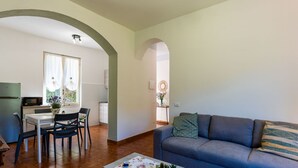 A living room with a sofa and a coffee table, a dining area with a table and chairs, and a kitchen with a microwave.