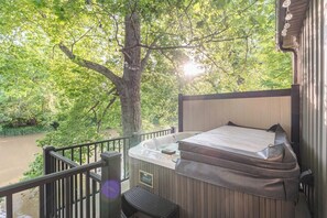 Ein Whirlpool auf einem Balkon mit Blick auf einen Fluss und Bäume.