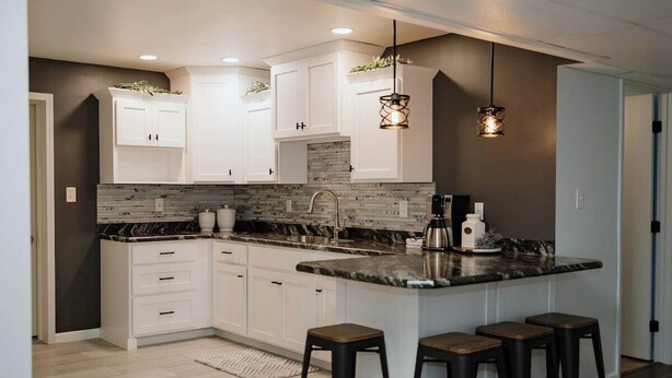 A modern kitchen with white cabinets, a marble countertop, and bar stools. - Pleasant Acres - Pleasant Acres (Greenville)