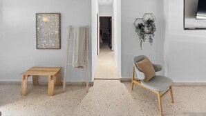 Ein modernes Zimmer mit einem Holztisch, einem Stuhl, einer Leiter und einer Wandpflanze.