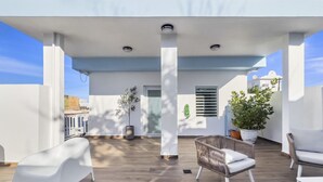 Eine moderne Terrassenanlage im Freien mit weißer Möbel, einem Topfpflanzen und Blick auf die Stadt.