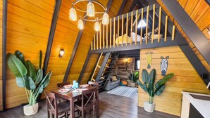 Een gezellig zolderkamer met een eethoek, houten wanden en een hoogslaper.