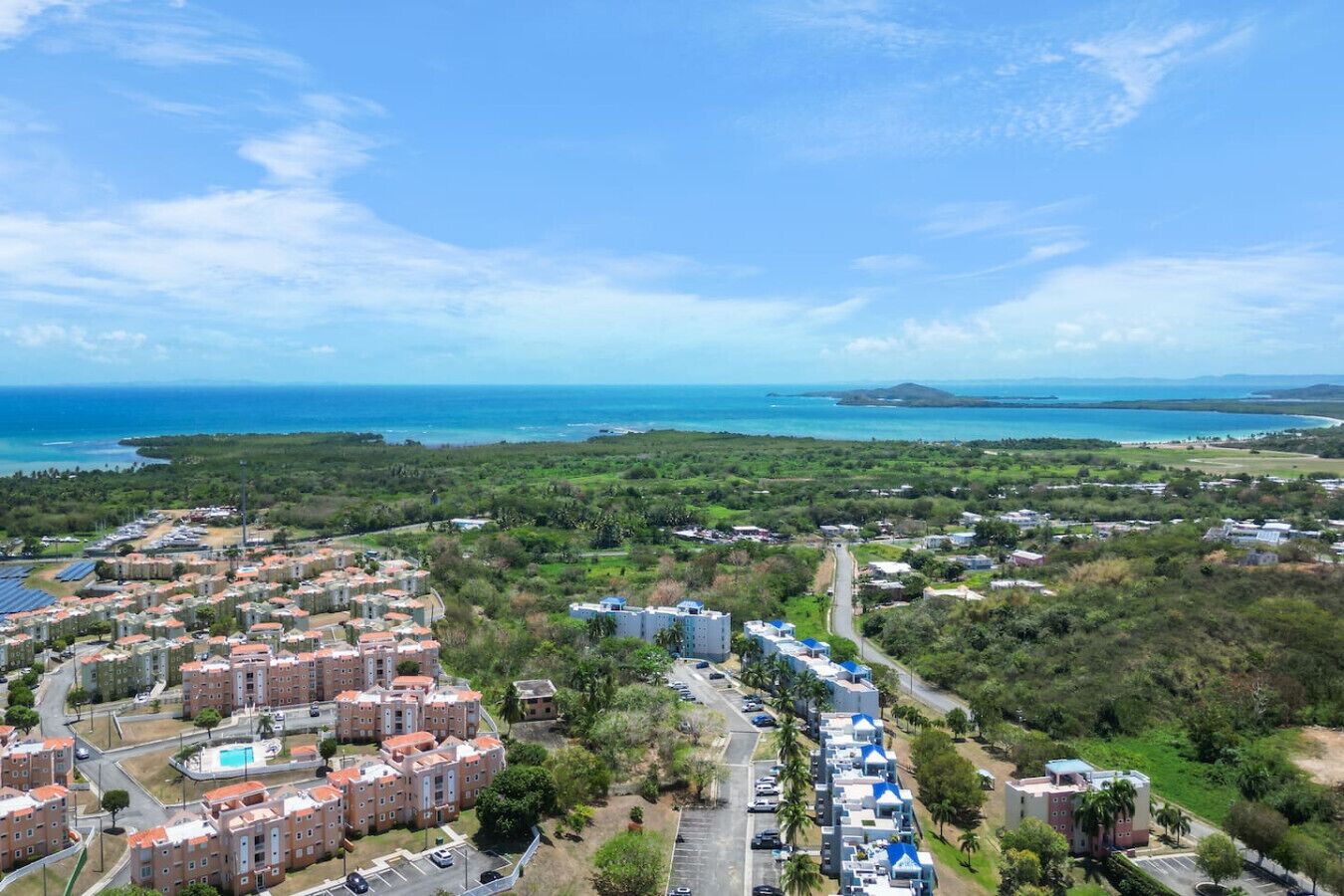 Zona residencial con edificios de apartamentos, una piscina y vistas al océano.