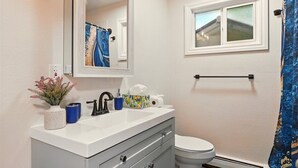 A bathroom with a white sink, a mirror, a toilet, and a window.