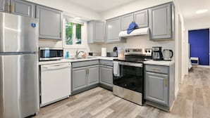 A modern kitchen with grey cabinets, stainless steel appliances, and a window providing natural light.