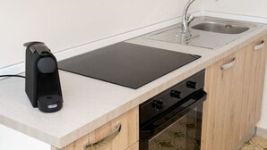 A compact kitchen with a built-in stove, a sink, and a portable heater.