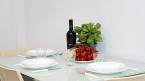 A dining table set with white plates, cutlery, and a bottle of wine.