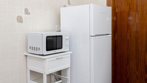 Una cocina con un refrigerador blanco y un microondas sobre un mueble blanco.