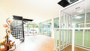 A modern interior with a spiral staircase, wooden flooring, and glass doors leading to outdoor areas.