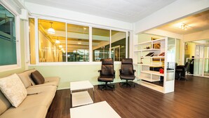 A modern office space with a sofa, two chairs, a white table, and a bookshelf.