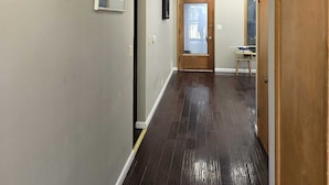 A hallway with dark wooden flooring, light gray walls, and framed artwork.