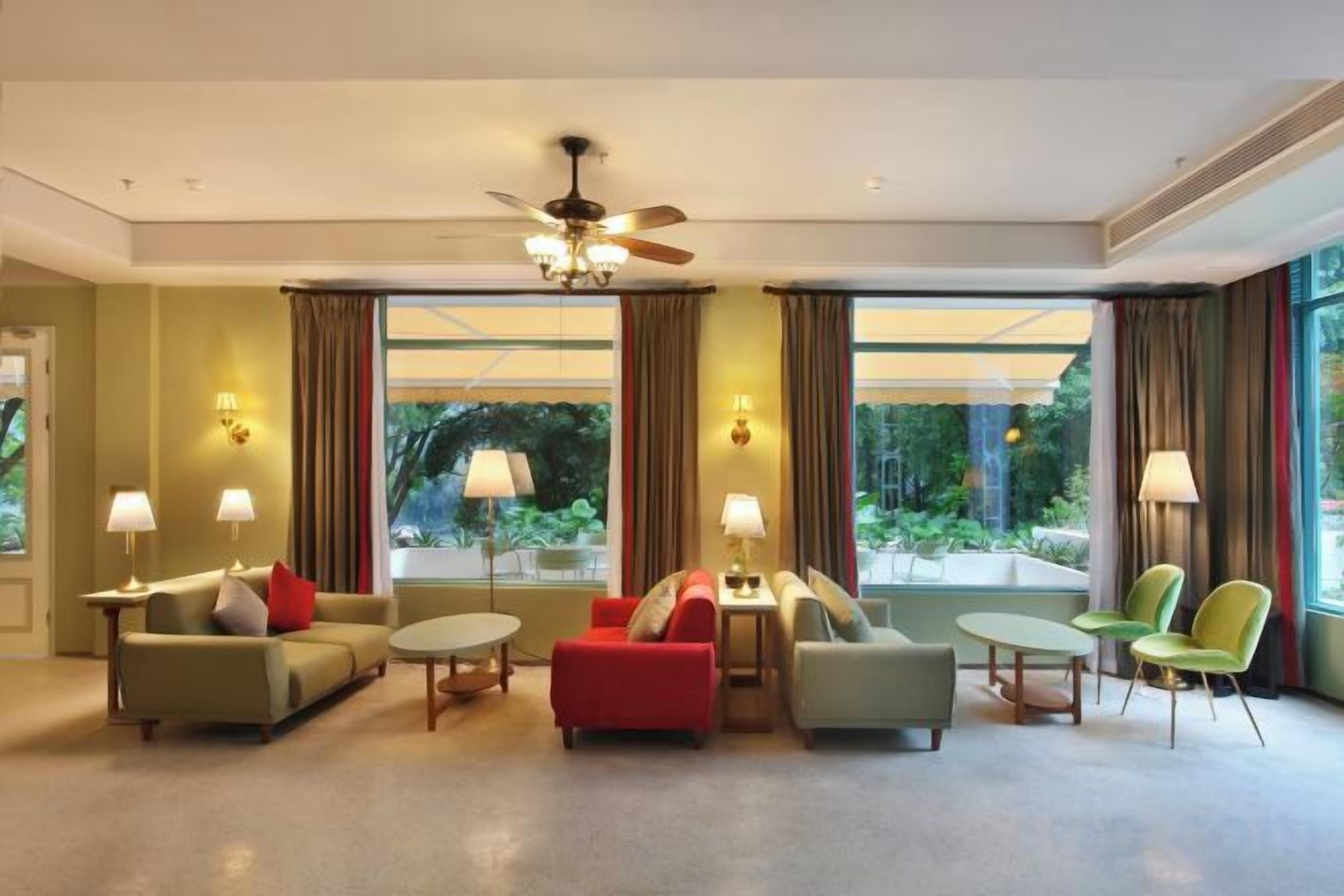 A hotel room with a sofa set, armchairs, a coffee table, and a ceiling fan.
