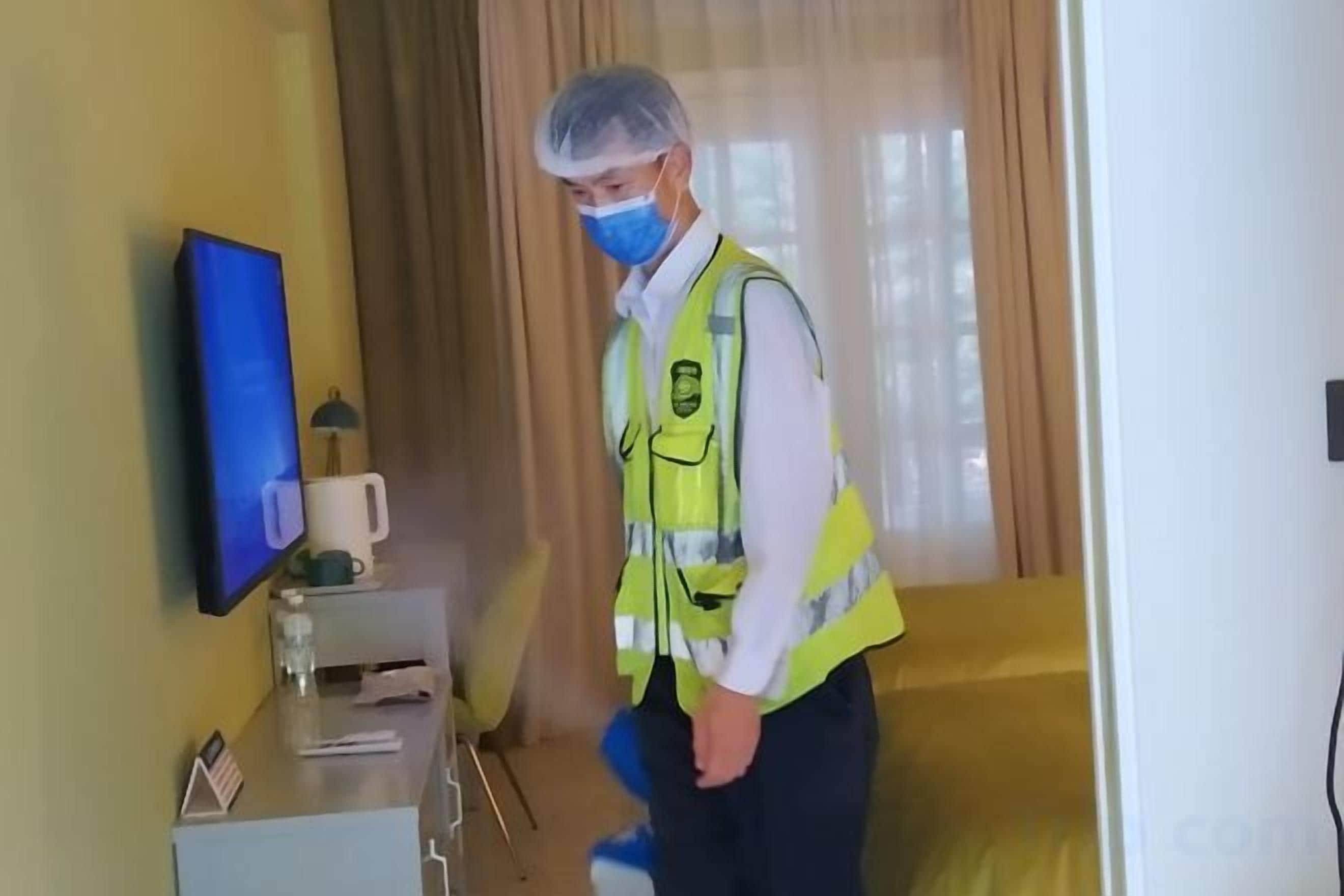 A hotel room with a bed, a bedside table with a lamp, a TV, and a window with curtains.