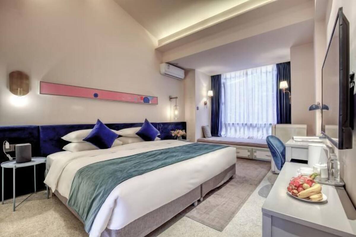 A hotel room with a bed, bedside table, desk, and a television.