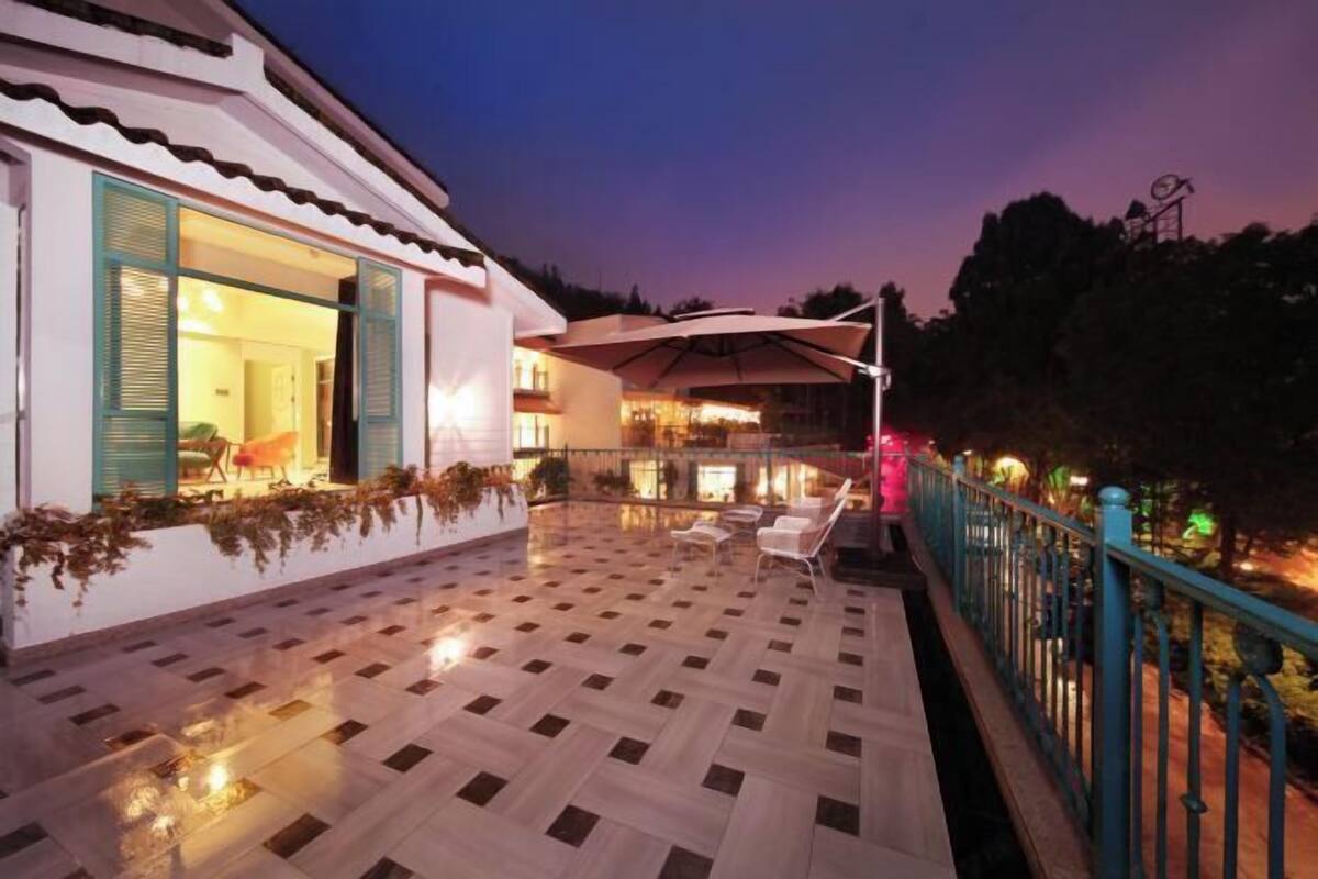 A hotel with a tiled patio, outdoor seating, and a railing.
