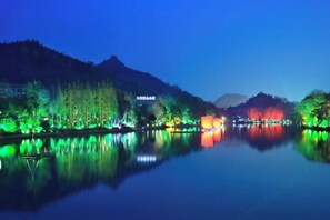 A calm lake at night with illuminated trees and buildings reflecting on the water. - Julan'an Homestay (Guilin Liangjiang Sihu Dongxi Alley Shop) (Guilin)