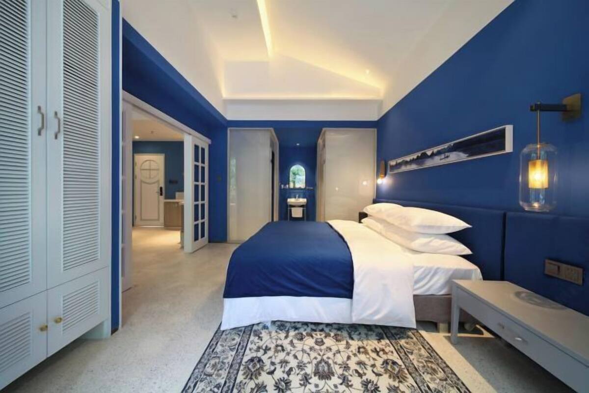 A bedroom with a bed, bedside table, and a wall-mounted lamp.