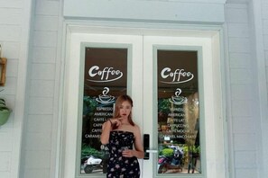 A person standing in front of a door with a sign that reads 'Coffee' and lists various coffee types. - Julan'an Homestay (Guilin Liangjiang Sihu Dongxi Alley Shop) (Guilin)