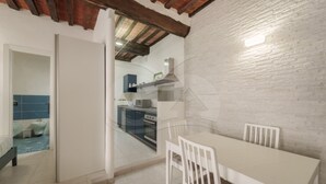 A modern kitchen with a dining area, featuring a white table and chairs, a kitchen island, and a brick accent wall.