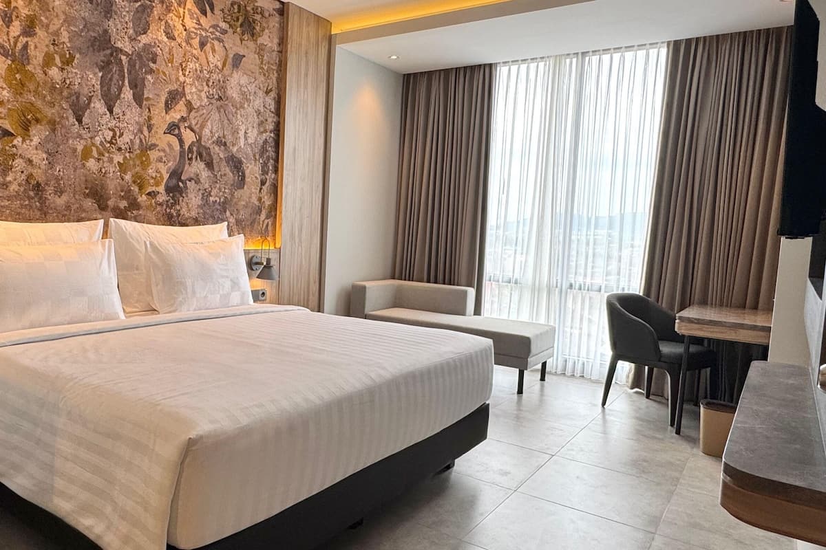 Een moderne hotelkamer met een groot bed, een bureau en een stoel.