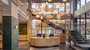 A modern reception area with a central desk, multiple hanging lights, and a staircase.