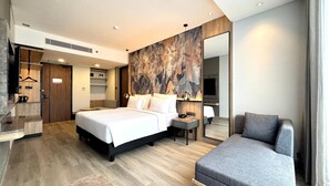 A modern hotel room with a large bed, bedside table, and a seating area with a sofa.