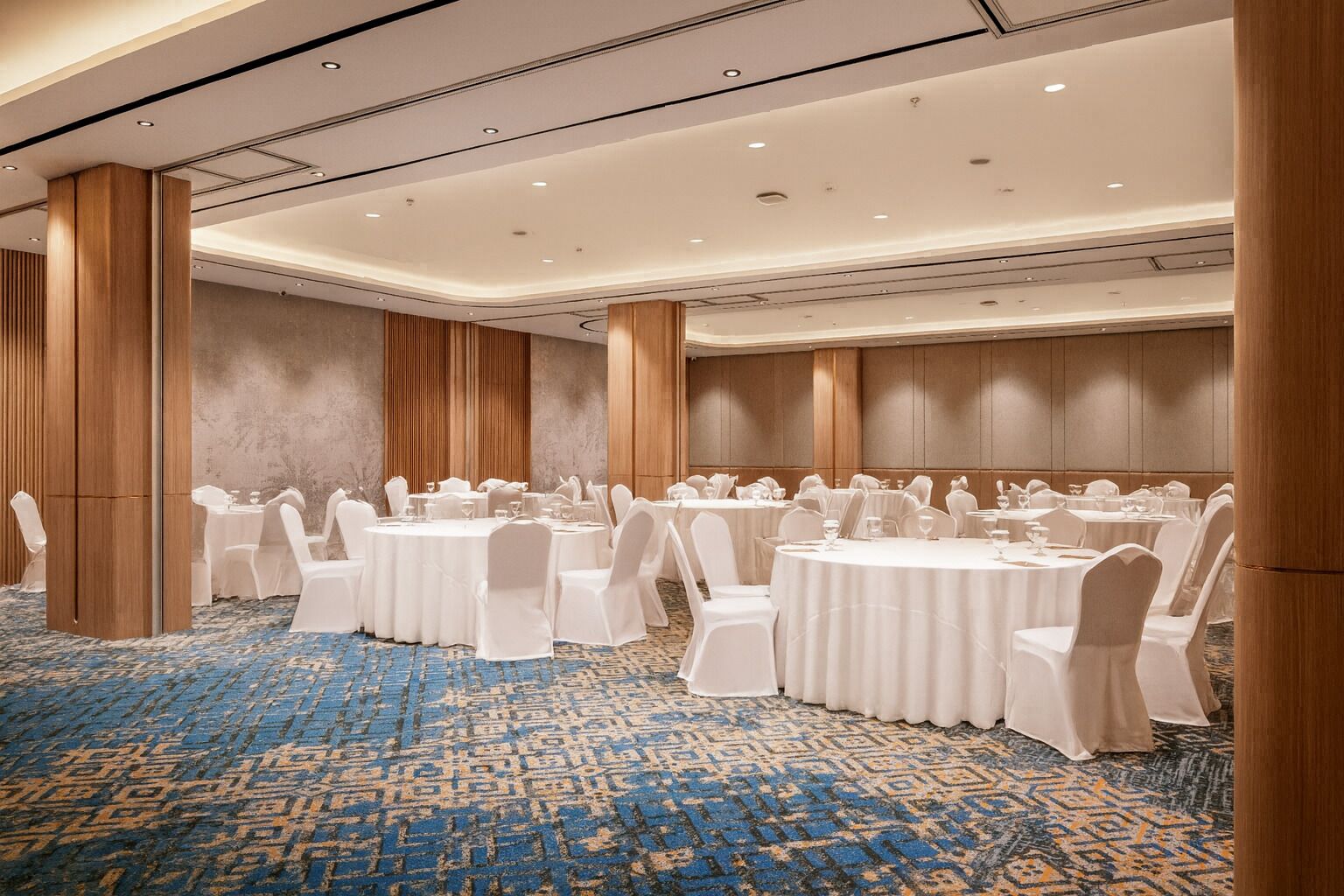 A conference room with round tables, white chairs, and a patterned carpet.