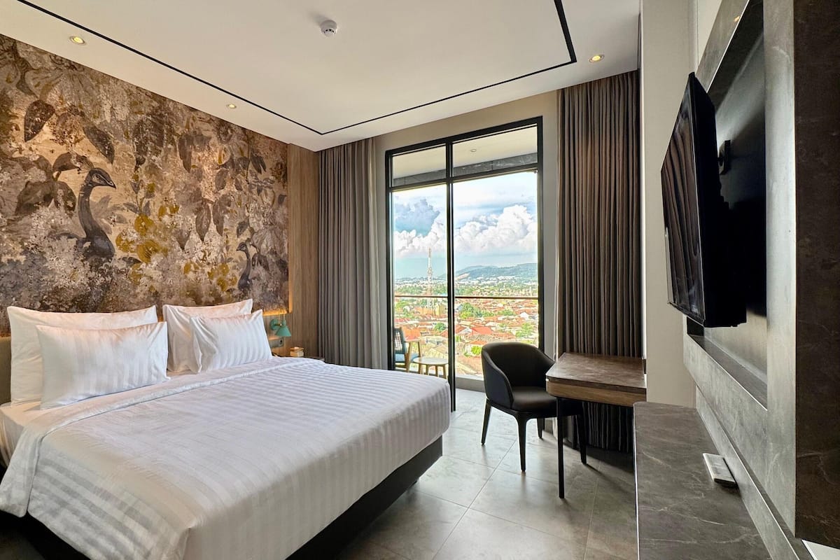 Een moderne hotelkamer met een groot bed, een bureau en uitzicht over de stad.