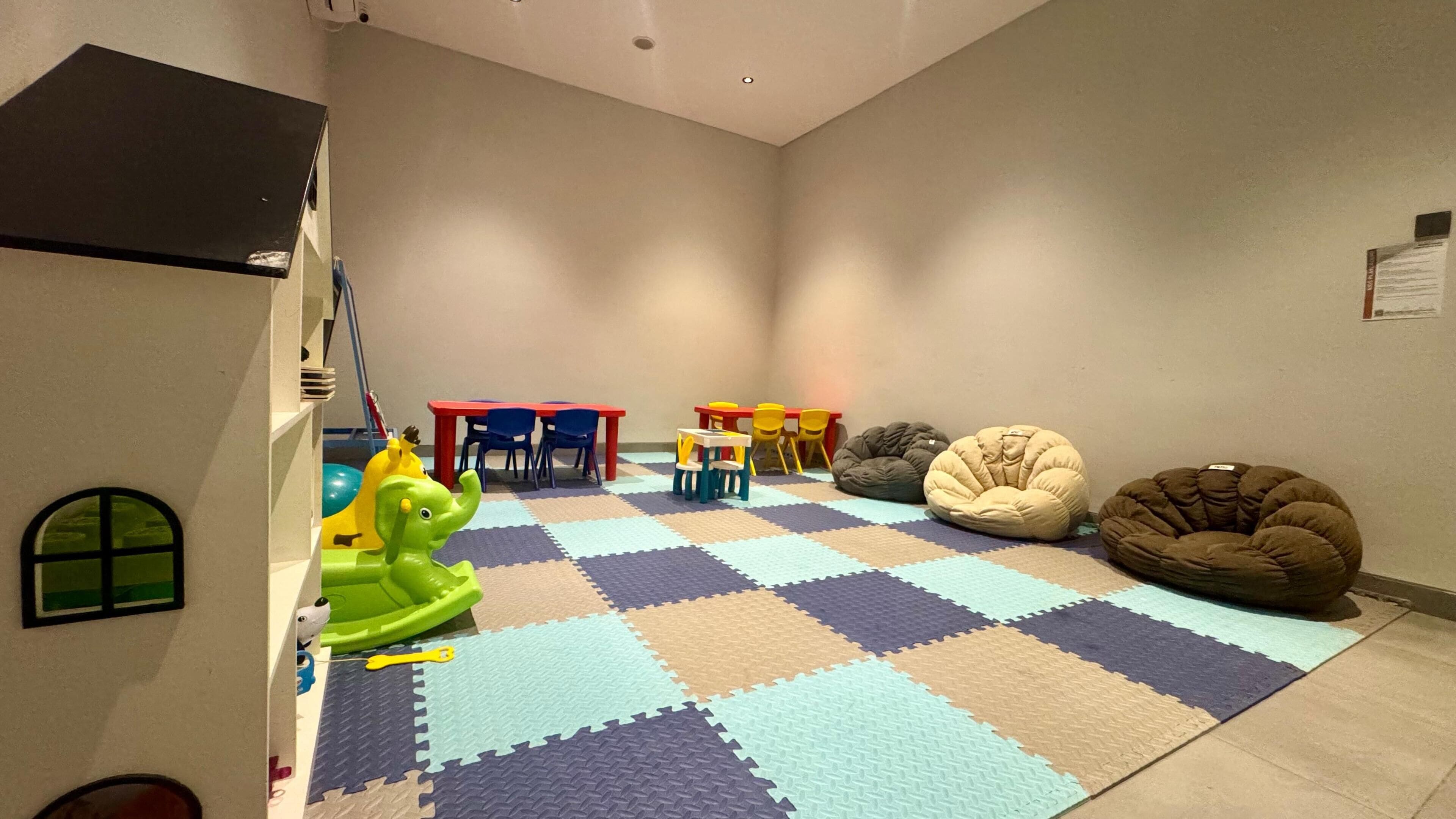 A children's play area with a checkered floor, colorful chairs, and bean bags.