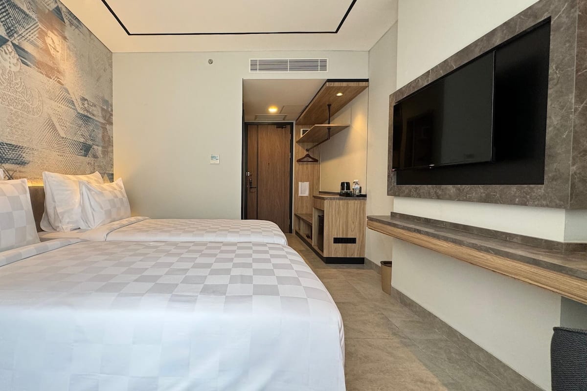 Een hotelkamer met een groot bed, een aan de muur bevestigde televisie en een klein kitchenette.