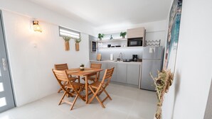 A modern kitchen with a dining area, featuring a wooden table and chairs, a microwave, and a refrigerator. - Oceanfront Retreat w/ Terrace, Direct access to Beach & BBQ (Mayaguez)