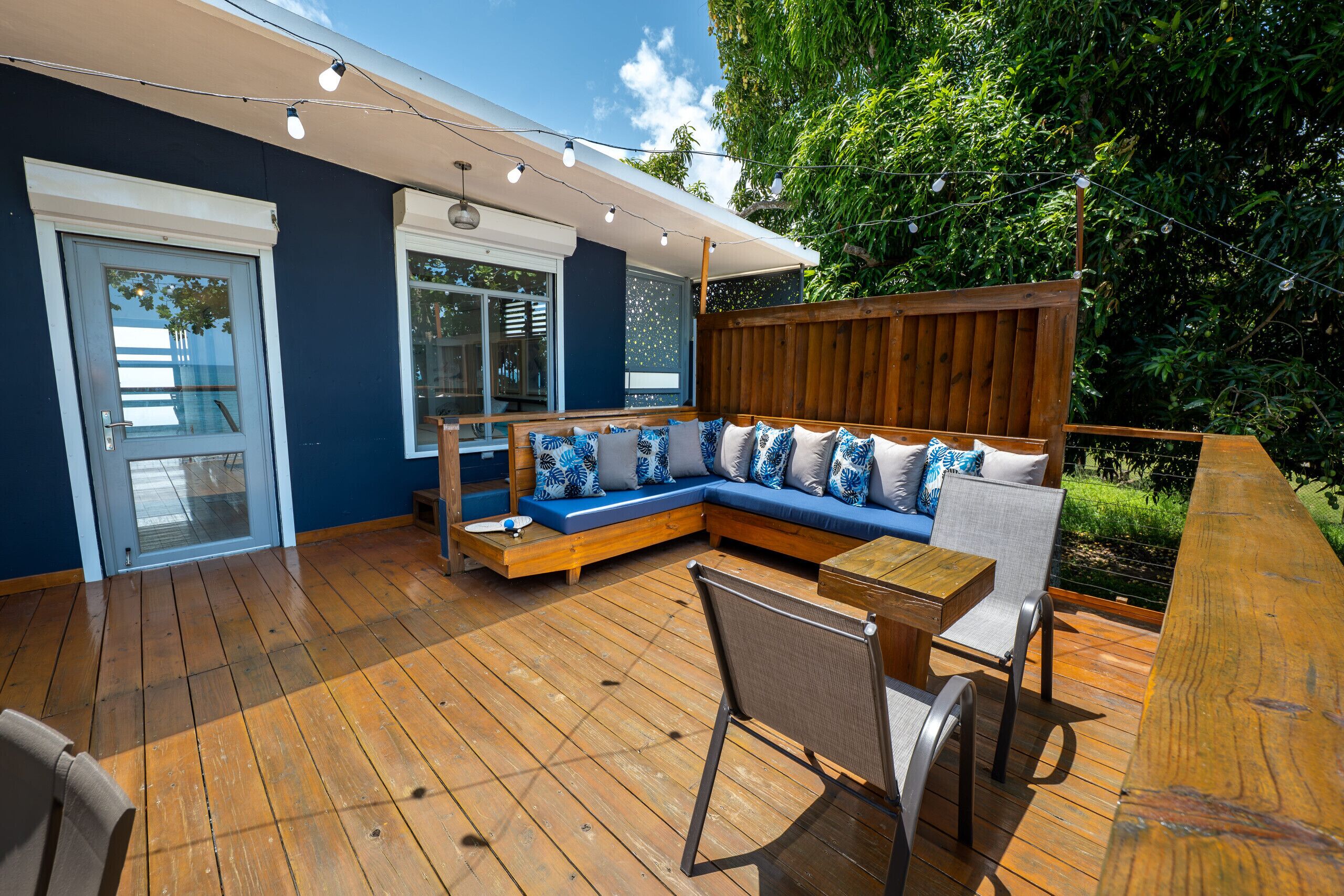 A wooden deck with a built-in sofa, a dining table, and chairs.