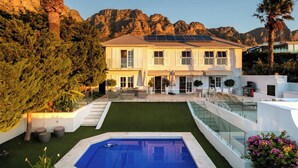 A two-story house with a swimming pool, solar panels, and a view of mountains. - Incredible 6bed w Pool in Camps Bay Villa Galazzio (Cape Town)