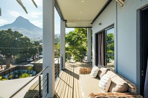 A balcony with a view of a mountain, wicker furniture, and a railing.