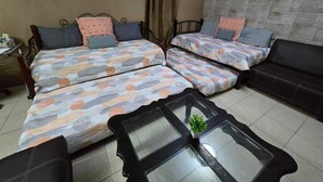 Habitació amb dos llits, un sofà, una taula petita i un aparell d'aire condicionat.