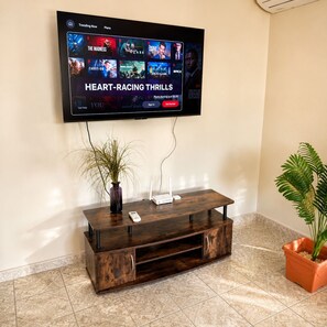 A flat-screen TV mounted on a wall displaying a streaming service interface with a 'Heart-Racing Thrills' section.